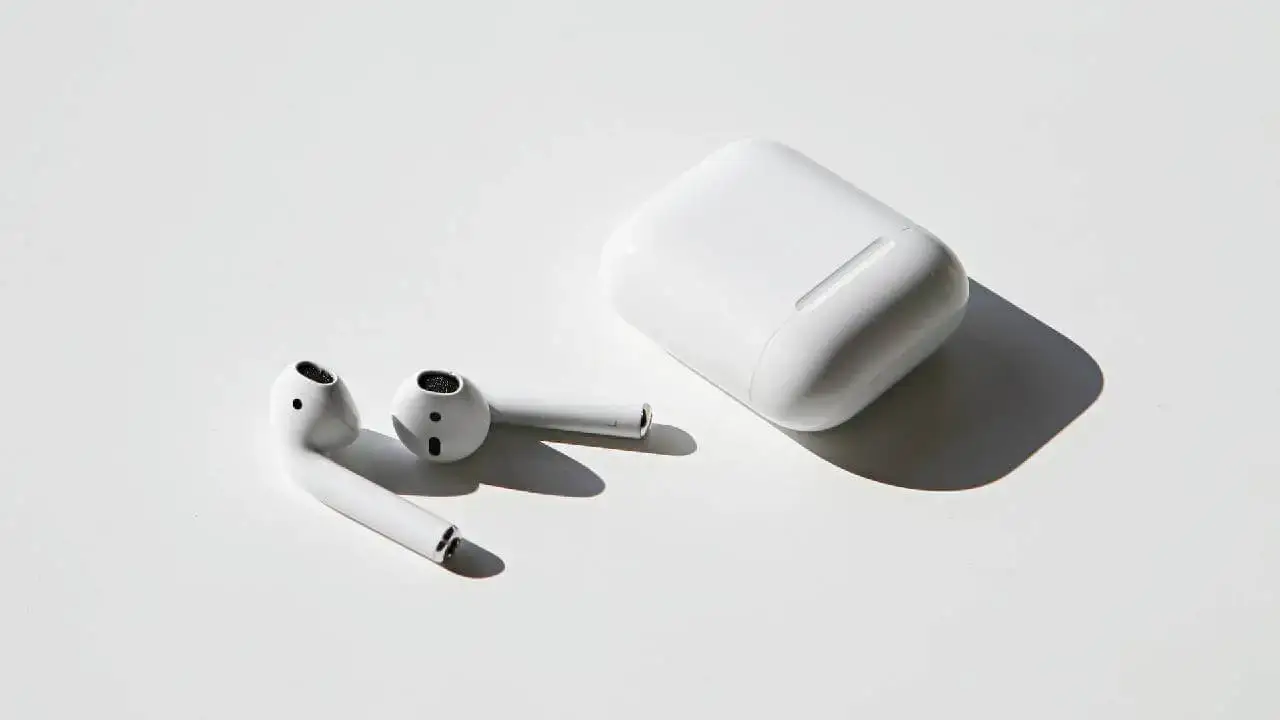 Photo of Apple AirPods on white table with case beside them
