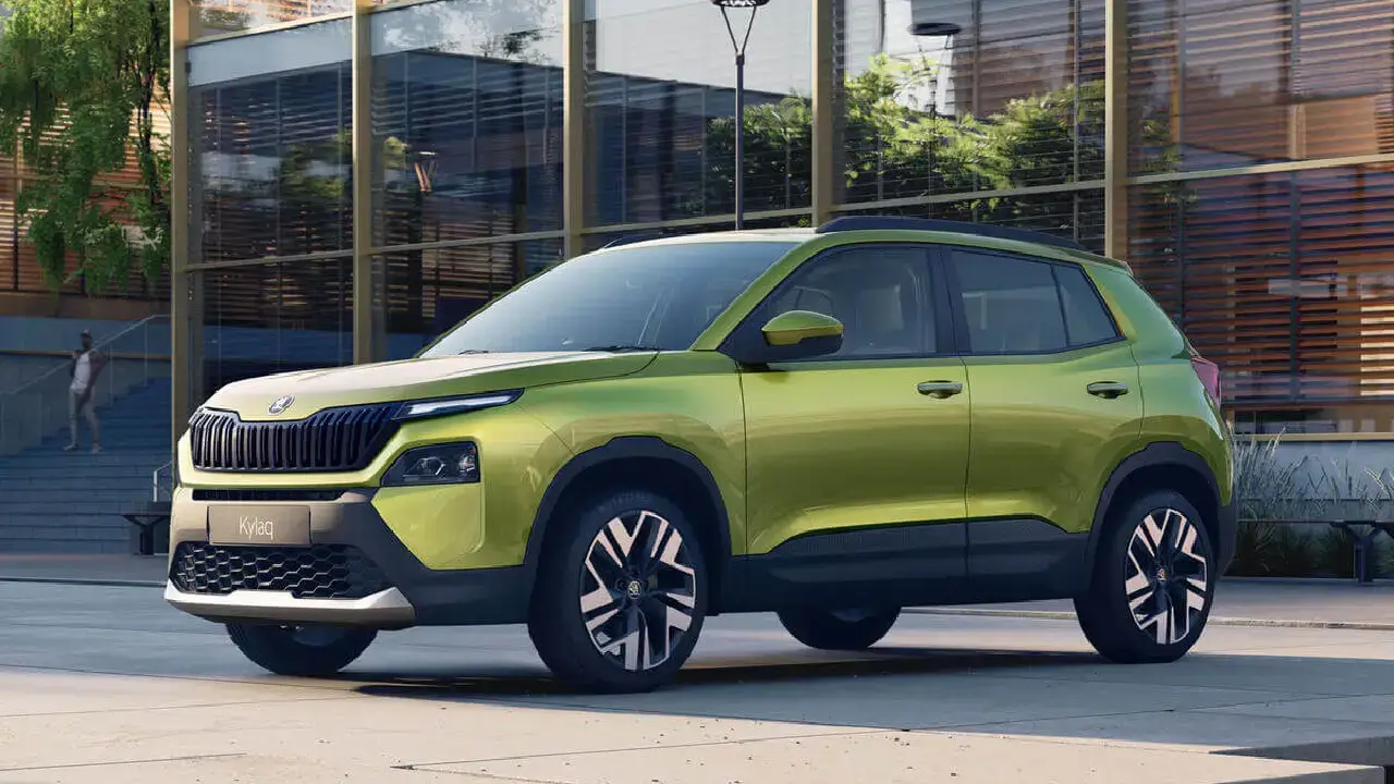 Schräge Frontansicht des kompakten Skoda Kylaq SUV in markantem Olivgrün. Das Crossover-Modell zeigt sein modernes Split-Headlight-Design und Bicolor-Felgen vor einer modernen Glasfassade
